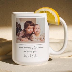 May include: White ceramic mug with a photograph of two children, a lemon slice, and the text "Good morning Grandma, we love you! Kira & Nate."