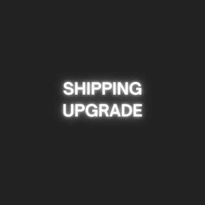 May include: A black background with the white neon text "SHIPPING UPGRADE" in the centre. The text glows brightly, providing a strong contrast. The image is simple and direct, with a clear message.
