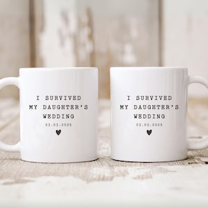 May include: Two white ceramic mugs with black text that reads "I survived my daughter's wedding 03.03.2025" and a small black heart.