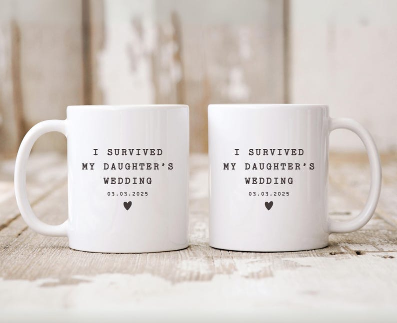 May include: Two white ceramic mugs with black text that reads "I survived my daughter's wedding 03.03.2025" and a small black heart.
