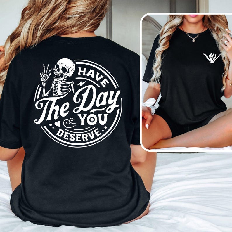 May include: Black t-shirt with a white graphic on the back that says "Have the Day You Deserve" with a skeleton holding a peace sign. The graphic is in a circle with a lightning bolt and hearts.