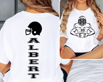 May include: White t-shirt featuring a black football helmet graphic and the name "ALBERT" in a vertical layout. The shirt also displays a black and white illustration of a football player wearing a helmet and holding a football, with the number "10".