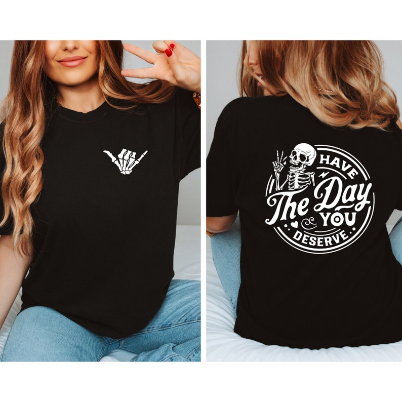 May include: Black t-shirt with a white skeleton hand making a shaka sign on the front and a white circle on the back with a skeleton holding a peace sign and the text "Have The Day You Deserve."