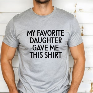 May include: A grey t-shirt with the text "My favourite daughter gave me this shirt" printed in black.