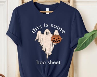 May include: A navy blue t-shirt with a white ghost holding a pumpkin and the text "this is some boo sheet".