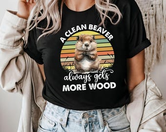 May include: A black t-shirt with a retro sunset graphic and a cartoon beaver. The text reads "A Clean Beaver Always Gets More Wood".