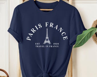 May include: A navy blue t-shirt with a white graphic of the Eiffel Tower and the text "Paris France Est 1928 Travel in France".