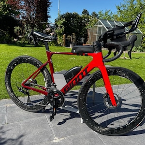 Puede incluir: Una bicicleta de carretera Giant roja con ruedas negras y un manillar negro. La bicicleta tiene un sillín negro y una jaula para botellas de agua negra.