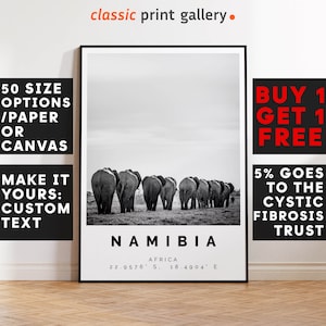 Könnte beinhalten: Schwarz-Weiß-Druck mit einer Elefantenherde, die in Namibia über eine Grasfläche zieht. Der Druck trägt die Aufschrift "Namibia" mit Koordinaten und den Text "classic print gallery."