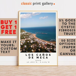 Könnte beinhalten: Ein gerahmter Druck von Los Caños de Meca, Spanien, mit einer Küstenansicht mit Strand und Gebäuden. Der Druck enthält die Koordinaten des Ortes und den Text "classic print gallery." Zusätzlicher Text wirbt für ein "Kaufe 1, erhalte 1 gratis" Angebot und unterstützt den Cystic Fibrosis Trust.
