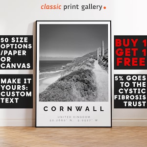 May include: Black and white framed print of Cornwall, United Kingdom, featuring a coastal landscape with a path leading to a historic structure. The print includes the text "Cornwall" and coordinates. The print also includes the text "50 SIZE OPTIONS / PAPER OR CANVAS" and "MAKE IT YOURS: CUSTOM TEXT".