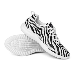 Puede incluir: Zapatillas deportivas blancas con un estampado de rayas de cebra negras. Las zapatillas tienen cordones y suelas blancas. Se ve la suela de una zapatilla, mostrando un patrón texturizado. Diseñadas para comodidad y estilo.