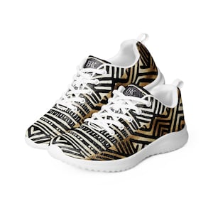 May include: A pair of athletic shoes with a black, white, and gold geometric pattern. The shoes have white laces, a white sole, and a white interior. The shoes are designed for running or walking.