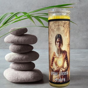 May include: A yellow candle with a gold and brown label featuring a woman with a golden halo and the text "solar plexus chakra".