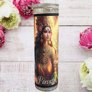 May include: A white pillar candle with a colorful image of the Hindu goddess Parvati. The image shows her with a golden crown, jewelry, and a red and gold dress. The candle is labeled "Parvati" at the bottom.