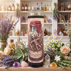 May include: A tall cylindrical candle in a glass jar featuring a label with a voodoo doll illustration inside a glass bottle, topped with red wax, and the word "BINDING" printed at the bottom. The candle is surrounded by lavender, roses, and crystals.