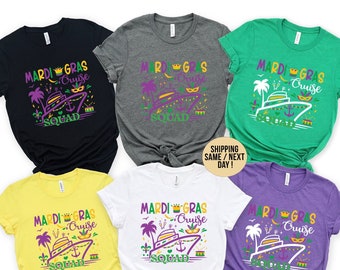 Op de afbeelding: Zes verschillende gekleurde T-shirts met de tekst "Mardi Gras Cruise Squad" en een afbeelding van een cruiseschip, palmbomen en een kroon. De shirts zijn in zwart, grijs, groen, geel, wit en paars.