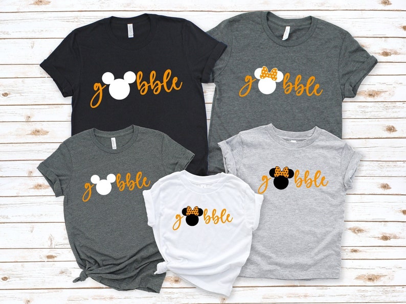 Peut inclure: Quatre t-shirts avec une t&ecirc;te de Mickey Mouse et le mot "gobble" imprim&eacute; dessus. Les t-shirts sont de diff&eacute;rentes couleurs&nbsp;: noir, gris, blanc et gris clair. Les t&ecirc;tes de Mickey Mouse sont de diff&eacute;rentes couleurs&nbsp;: blanc, noir et blanc avec des pois orange.