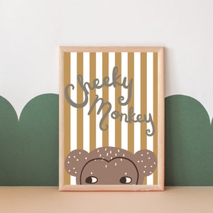 May include: A framed print with a yellow and white striped background. The text "Cheeky Monkey" is written in grey script. A brown monkey face peeks out from behind the stripes.