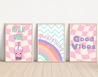 May include: Three framed prints with pink and white checkered backgrounds. The left print features a pink bubble tea with a green straw and the text "It's a Vibe". The middle print features a rainbow with a green, blue, and purple background and the text "Positivity". The right print features the text "Good Vibes" in purple.