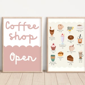 May include: Two framed prints, one with the text "Coffee Shop Open" in white on a pink background and the other with a menu of coffee and pastry items with prices in pounds sterling.