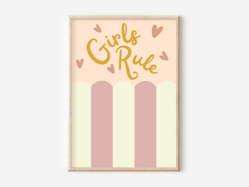 May include: A pink and yellow striped print with the text "Girls Rule" in gold lettering and small hearts scattered around the text. The print is framed in a light wood frame.