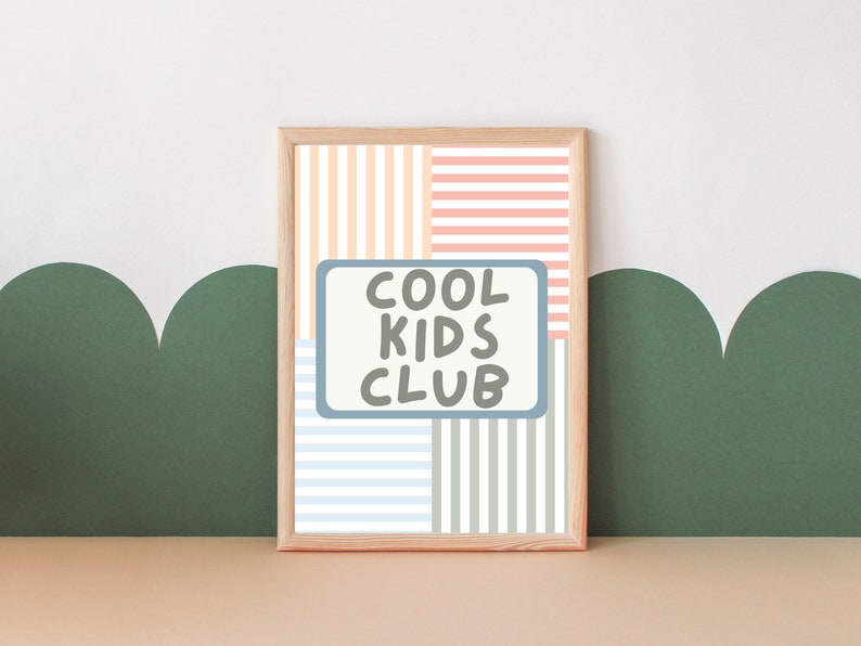 May include: A framed print with a striped background in shades of pink, orange, blue, and green. The print features a white rectangle with the text "COOL KIDS CLUB" in black.