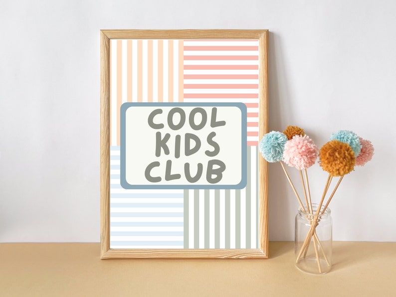 May include: A framed print with a striped pattern in peach, pink, blue, and gray. The print has the text "COOL KIDS CLUB" in a gray box.