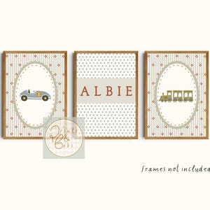 May include: Three framed prints with a vintage design. One shows a light blue race car, another the name "ALBIE" in red, and the third a train. Each print has a patterned background and a brown wooden frame.