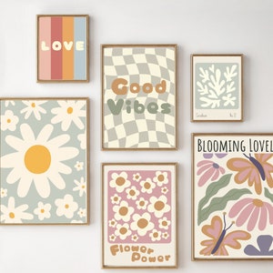 Op de afbeelding: Een set van 7 ingelijste prints met een retro 70s esthetiek. De prints bevatten verschillende ontwerpen, waaronder madeliefjes, vlinders, geruite patronen en de woorden "Love", "Good Vibes", "Flower Power" en "Blooming Lovely".