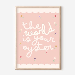 Pu&ograve; includere: Stampa artistica incorniciata con sfondo rosa chiaro e la frase "the world is your oyster" in corsivo bianco. Piccoli fiori colorati sono sparsi intorno al testo. La cornice &egrave; di colore legno chiaro.