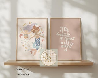 May include: Two framed art prints on a wooden shelf. One print features two mermaids with flowing hair and colorful tails. The other print has the text "The world is your oyster" in white script on a pink background. The prints are displayed on a shelf.