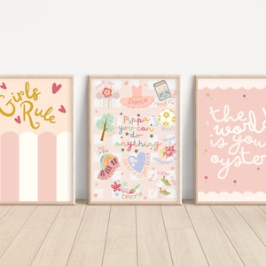 Pu&ograve; includere: Tre stampe artistiche incorniciate con citazioni e illustrazioni stimolanti. La prima stampa dice "Girls Rule" in lettere dorate. La seconda stampa ha il testo "Pippa you can do anything". La terza stampa dice "the world is your oyster".