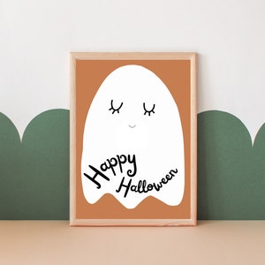 May include: A framed print with a white ghost illustration and the text "Happy Halloween" on a brown background.