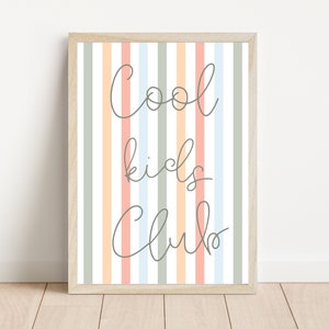 May include: A framed print with a striped background in shades of peach, light blue, and green. The text "Cool kids club" is written in a cursive font in gray.