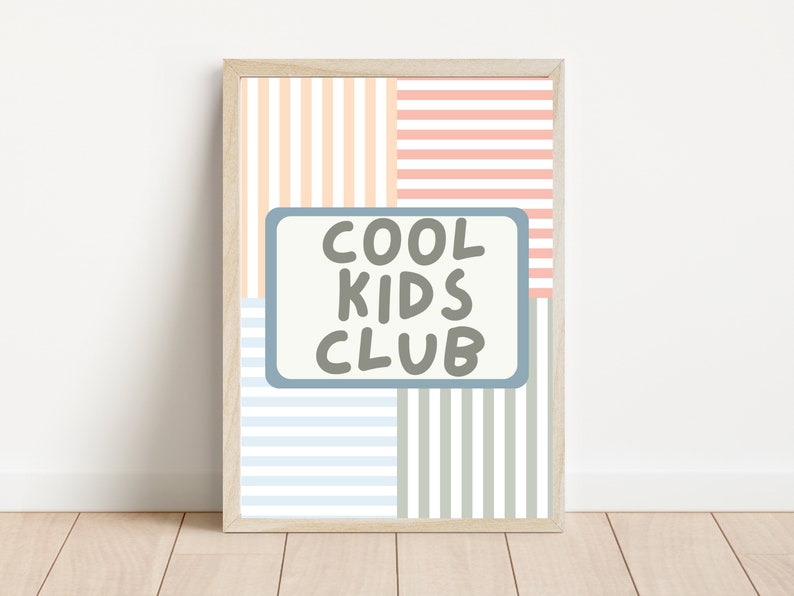 May include: A framed print with a striped background in shades of pink, peach, blue, and gray. The print features a blue rectangle with the text "COOL KIDS CLUB" in gray.
