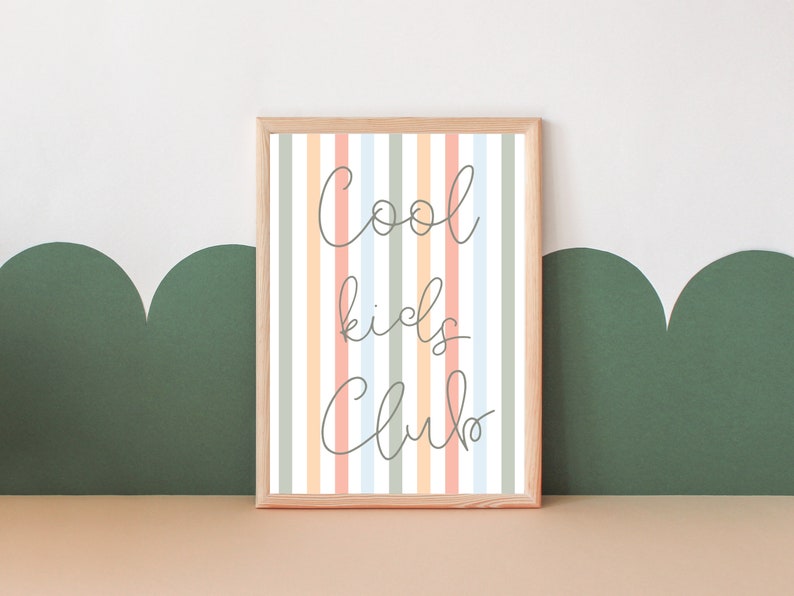 May include: A framed print with a striped background in shades of peach, light blue, and gray. The text "Cool kids club" is written in cursive on the print.