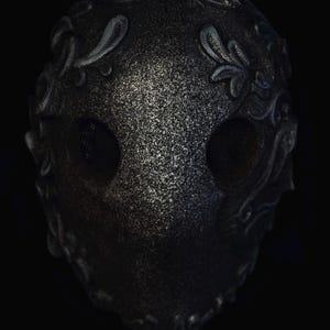 May include: A black masquerade mask with intricate silver floral designs and mesh eye coverings.