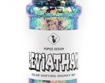 Peut inclure: Un flacon saupoudreur en plastique transparent rempli de paillettes épaisses aux reflets changeants dans des tons bleu, vert et or irisé. L'étiquette blanche porte une icône de chat noir, le texte POPOZ DESIGN, LEVIATHAN et COLOR SHIFTING CHUNKY MIX.