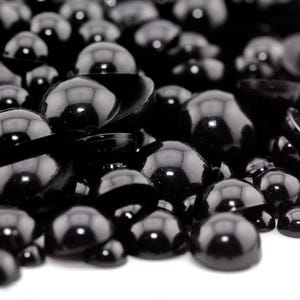 May include: A close-up shot of a pile of glossy, black, half-sphere glass beads. The beads have a smooth, reflective surface, with highlights creating a sense of depth. The beads are scattered, with some partially overlapping, against a white background.