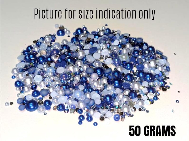 May include: A close-up of a pile of blue and white pearl beads, with a white background and the text "50 GRAMS" at the bottom.