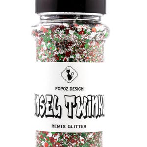 May include: A clear plastic bottle filled with red, green, and white glitter. The label reads "Tinsel Twink" and "Remix Glitter" with a black cat logo. The bottle has a black cap.