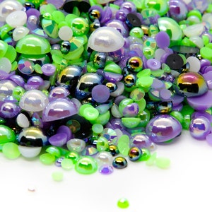 May include: A large assortment of colorful iridescent and opaque round and flat plastic cabochons in shades of green, purple, and white.