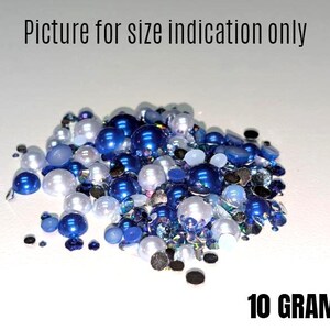 May include: A close-up of a pile of blue and white pearl-like beads and rhinestones. The beads are various sizes and shapes. The text "10 GRAMS" is visible at the bottom of the image.