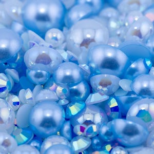 May include: A close-up of a collection of light blue iridescent pearl-like beads and rhinestones.