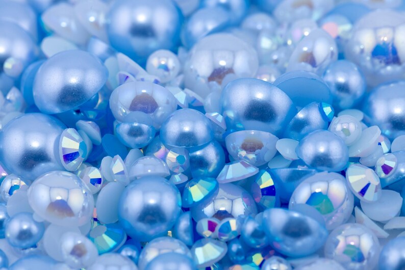 May include: A close-up of a collection of light blue iridescent pearl-like beads and rhinestones.