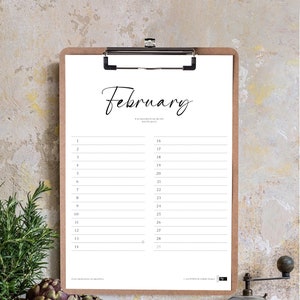 May include: A printable February calendar on a clipboard with a quote about the people who make life special. The calendar is on a wooden table with artichokes, a wooden bowl, a coffee grinder, and a small ceramic mug.
