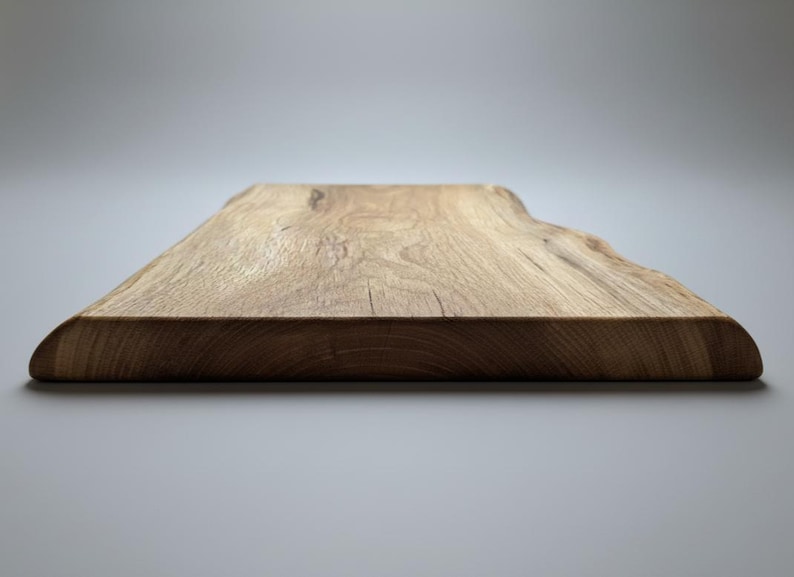 May include: A natural wood cutting board with a live edge. The rectangular board is made of light brown wood with visible grain and a smooth, curved edge. The board is approximately 1 inch thick.
