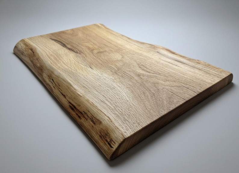 May include: A rectangular wooden cutting board with a natural edge. The board is made of light-colored wood with visible grain and a smooth, finished surface. The board is approximately 12 inches long and 8 inches wide.