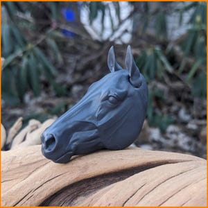 May include: A 3D printed horse head sculpture in a dark gray color. The sculpture is detailed and realistic, with a textured surface.